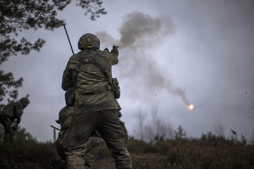 Een militair vuurt een wapen af.