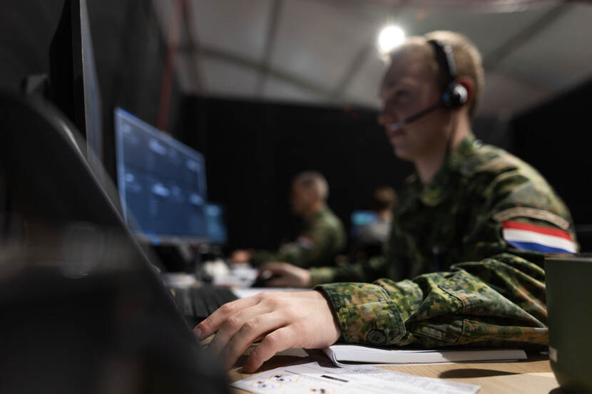 Een landmachtmilitair werkt achter zijn computer.