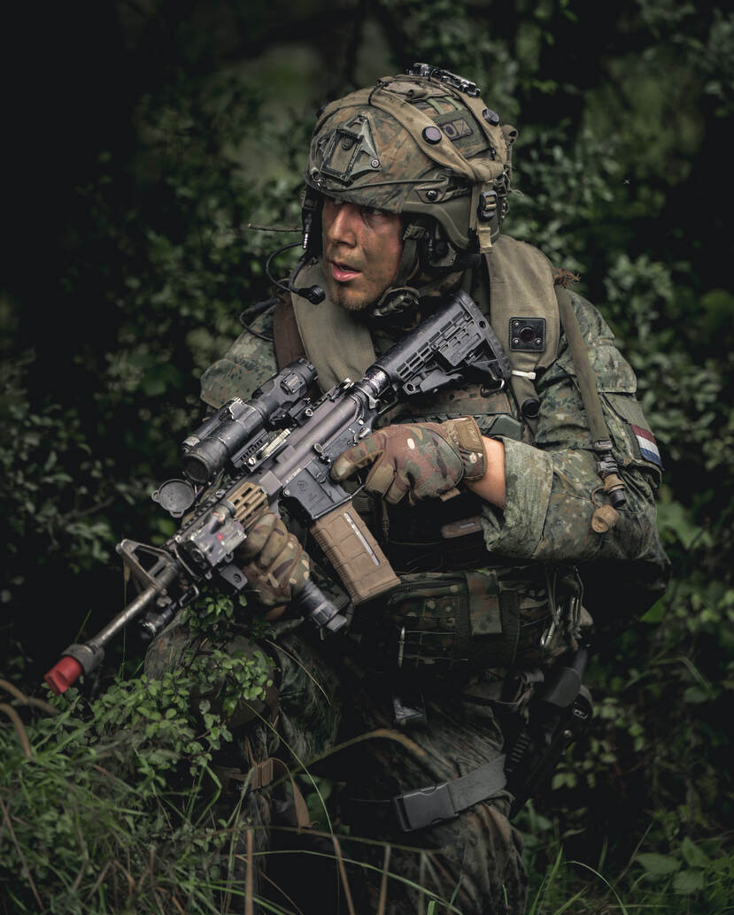 Vanuit de bosrand houdt een Nederlandse militair zijn sector nauwlettend in de gaten.