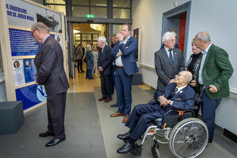 Tentoonstellingsruimte met diverse bezoekers onder wie een in een rolstoel.
