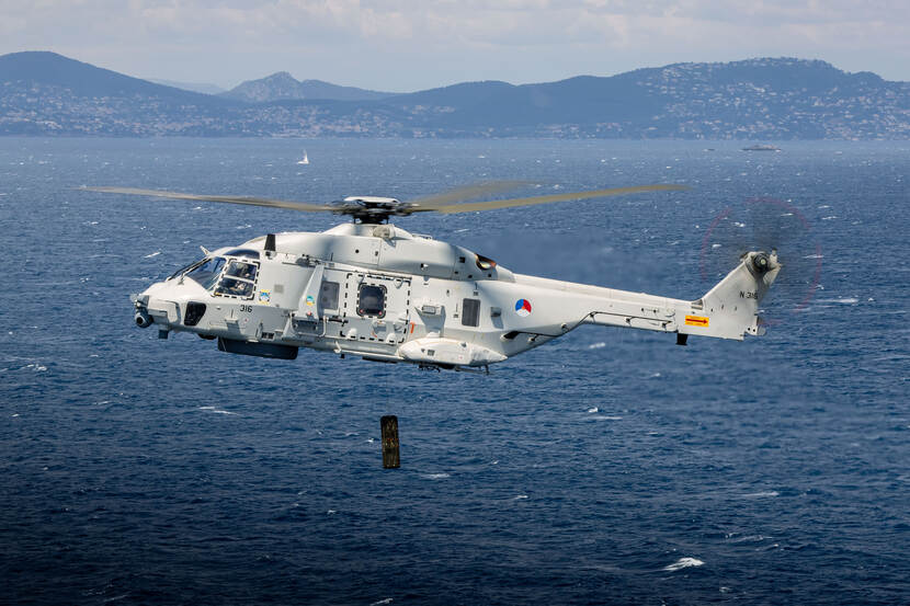 NH90 boven zee, op de achtergrond bergen.