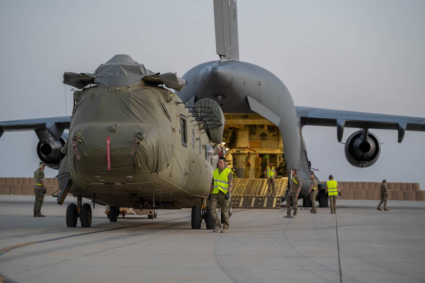 Transporthelikopter wordt in ruim vliegtuig geschoven.