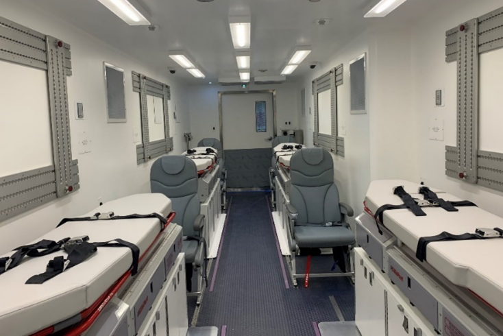 Witte containerruimte met vliegtuigstoelen en brancardbedden.