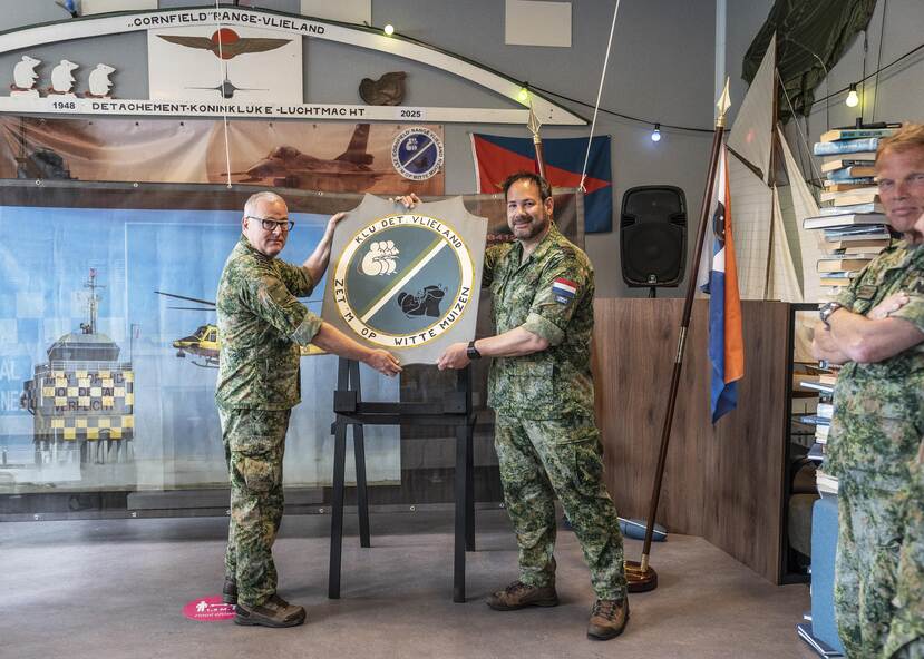 Duran overhandigt Van Keulen een bord met daarop een embleem met de tekst ‘KLu Det Vlieland, zet ‘m op witte muizen’.