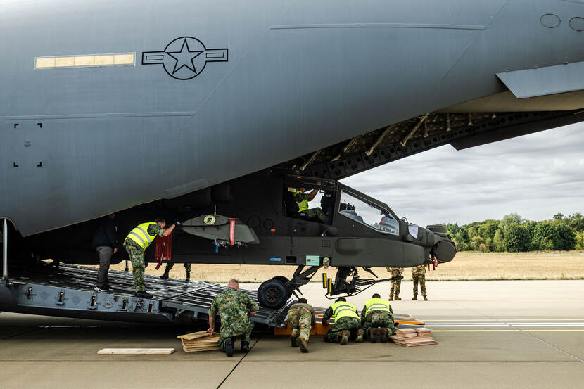 Apache rolt uit de ‘buik’ van een C-17, personeel begeleidt dit.