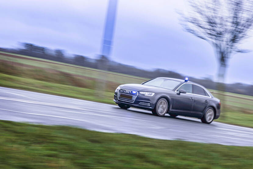 Auto van de Marechaussee rijdt op volle snelheid met blauwe zwaailichten aan.