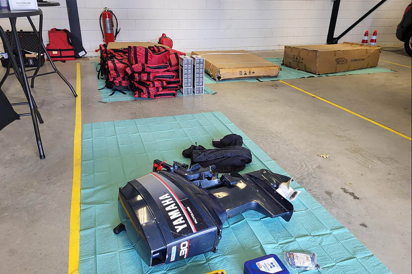 In een loods ligt een zware buitenboordmotor plus een stapel reddingsvesten.