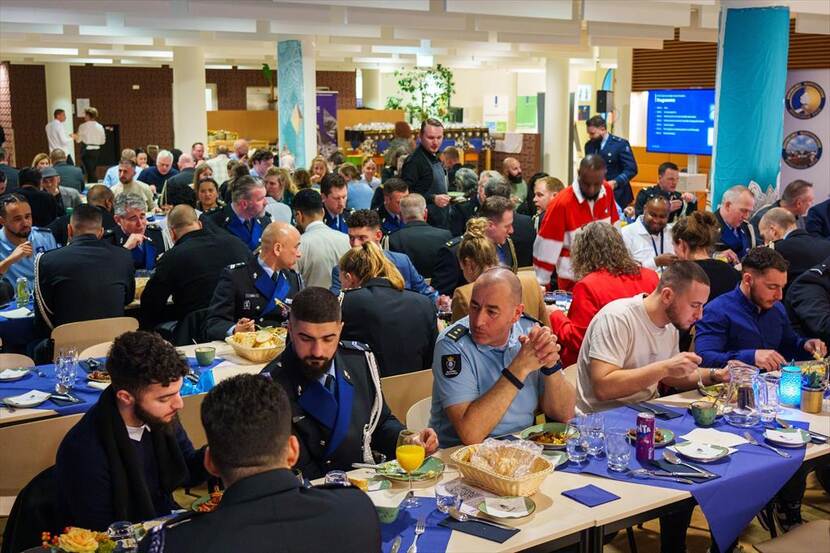 Tientallen Marechaussees zitten aan lange tafels om de Iftarmaaltijd te gebruiken.