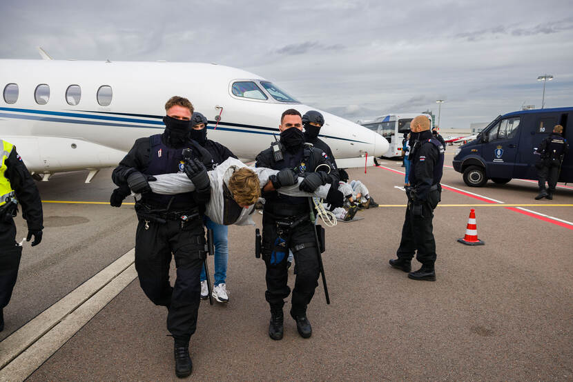 Marechaussees tillen een demonstrant weg.