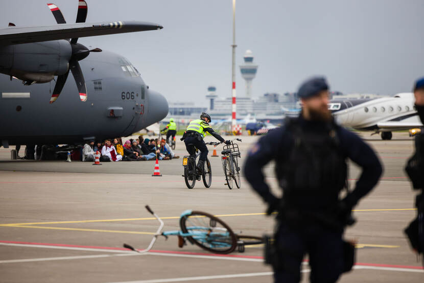 Een biker van de Marechaussees fietst met een andere fiets van 1 van de actievoerders aan zijn hand.