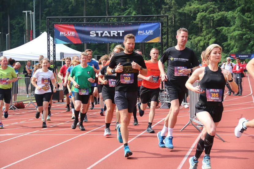 Deelnemers aan het Blue Light Event sprinten over de hardloopbaan.