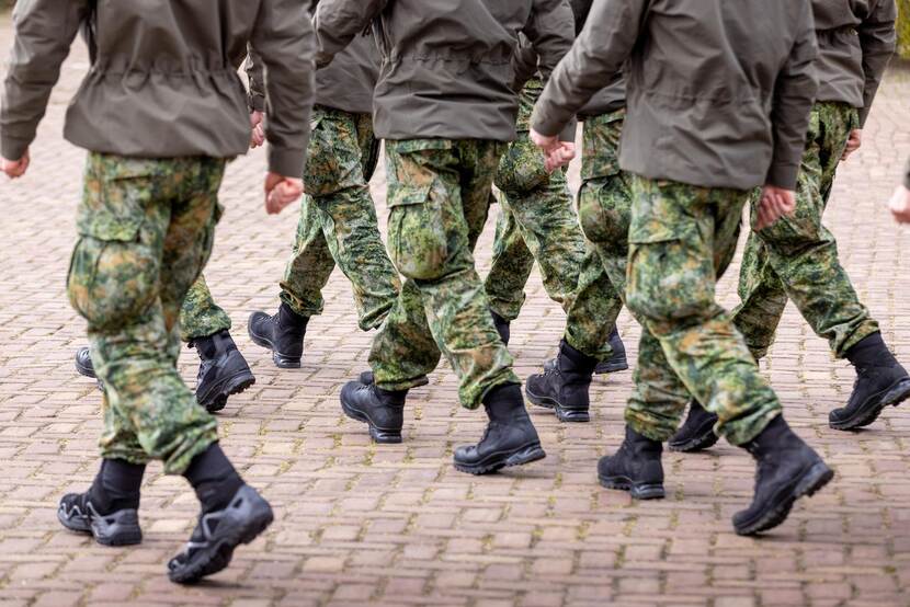Militairen in uniform lopen op een rij.