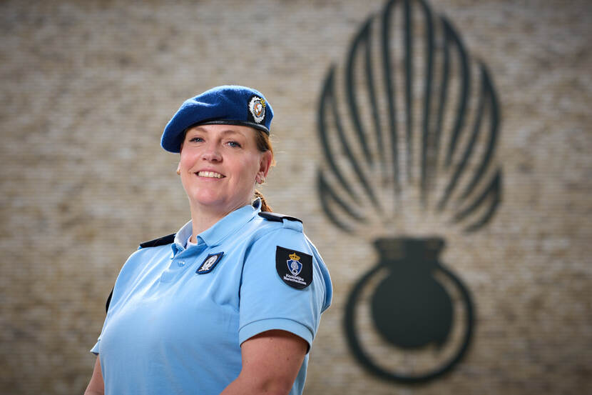Portretfoto van kolonel dr. Wendy Dorrestijn. Daarachter op een bruinige muur het zwarte logo van de Koninklijke Marechaussee.