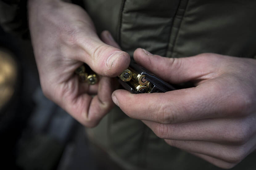 Hand die patronen in een patroonhouder stopt.