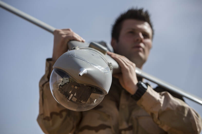 Militair met een drone op de schouder.