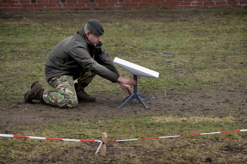 Een militair zet een Starlink-schotel op een grasveld.
