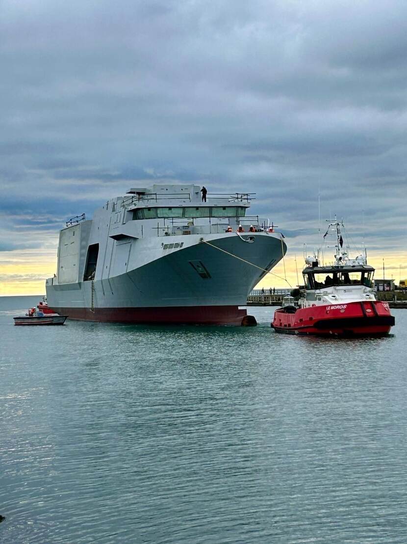 Het nieuwe mijnenbestrijdingsvaartuig wordt de haven binnen gesleept.