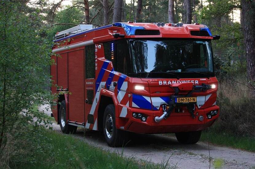Nieuwe brandweerwagen rijdt door een bos.