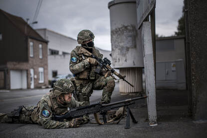 Twee mariniers met hun wapens in de aanslag, een liggend op de grond en de ander geknield.