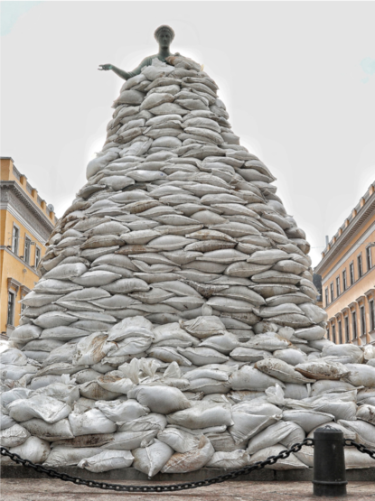 Een enorm groot beeld, totaal omringt door witte zandzakken. Alleen het hoofd steekt uit.