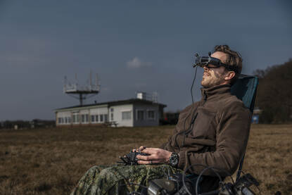 Een luchtmachter bestuurt een drone met een speciale bril op zijn hoofd.