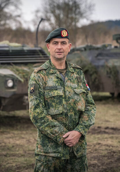 Foto van luitenant-kolonel Lenoir, met op de achtergrond militaire voertuigen