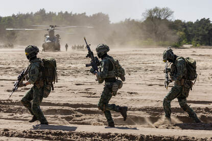 links: Een helikopter landt, rechts: militairen rennen over een stuk zand.