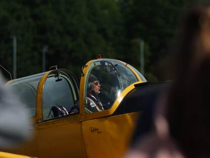 Historische vliegtuigen synchroon in de lucht en een piloot in zijn cockpit.