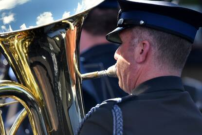 Een orkest treedt op op een goed gevuld plein, een muzikant bespeelt een blaasinstrument.