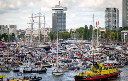 Overzicht van allerlei verschillende schepen op het water tijdens Sail, recht: Een menigte wacht om aan boord te kunnen van de Karel Doorman.