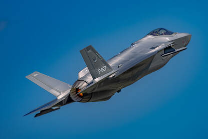 Een F-35 in volle vlucht, schuin van achteren gezien.