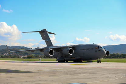 Militaire voertuigen op een treinstel. Rechts: Een militair vliegtuig landt.