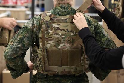 Een vrouwelijke militair krijgt een kogel- en scherfwerend vest voor vrouwen aangemeten.