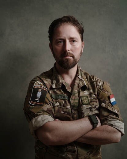 Portret van militair in uniform met handen over elkaar.