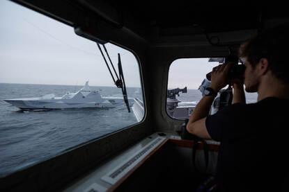 Vanaf een scheepsbrug turen door een verrekijker op zee.