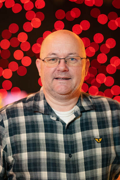 Man in blokblouse kijkt in de camera.