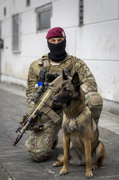 Portretfoto van hondengeleider Timo met de hond tussen zijn benen geplaatst.