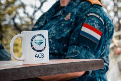 Een mok met daarop het logo van de F-WHAC.