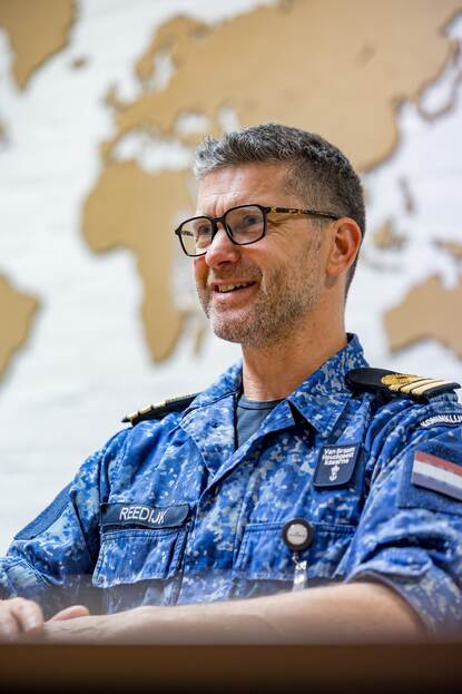 KLTZ (LD) Maartijn Reedijk zittend voor een bruine wereldkaart.