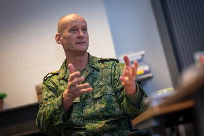 De Krijgsmachtadjudant gebaart met zijn handen tijdens een interview.