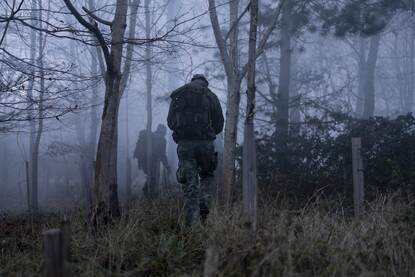 Mariniers lopen schietend voorwaarts en mariniers lopen in de mist door het bos.