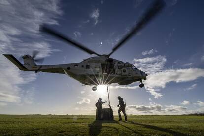 Mariniers rennen de NH90 uit en er hangt vracht onder de heli.