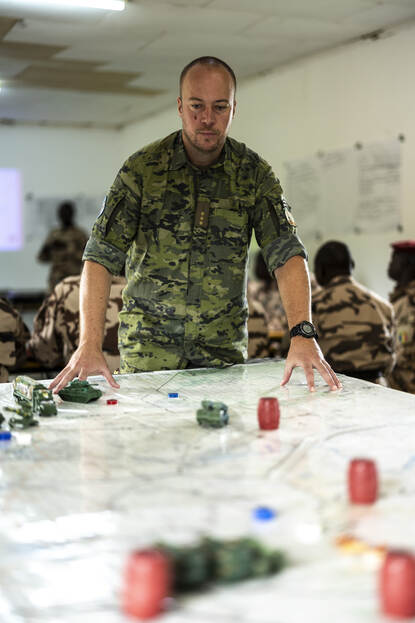 Kapitein Lowieke in het staflokaal. Achter hem geeft een Tsjadische instructeur zijn collega’s les.