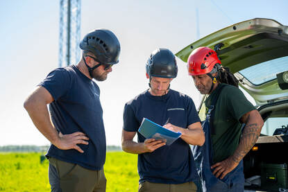 Drie technici met valhelm op gaan door een checklist heen.