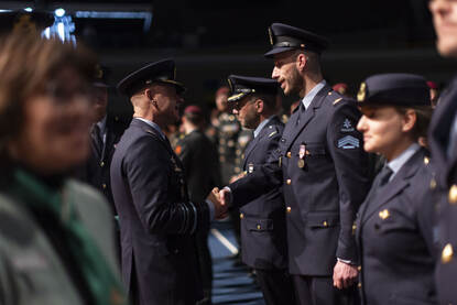 Links: overzichtsfoto van militairen opgesteld in een zaal. Rechts: luchtmachtmilitairen krijgen een medaille uitgereikt.