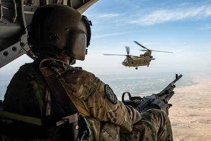 Een doorgunner met op de achtergrond een Chinook-transporthelikopter.