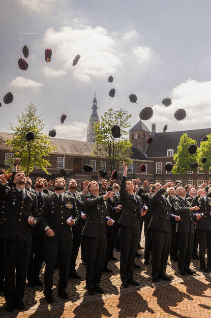 Militairen gooien hun baret in de lucht.