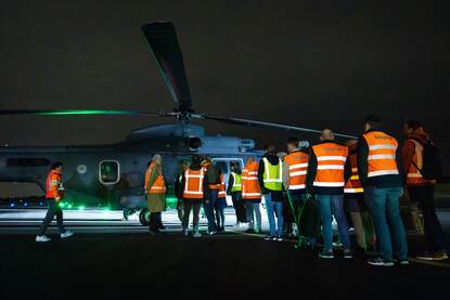 Figuranten in oranje hesjes stappen in het donker aan boord van helikopter.