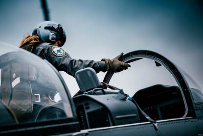 Een vlieger met helm op in de cockpit van een lesvliegtuig.