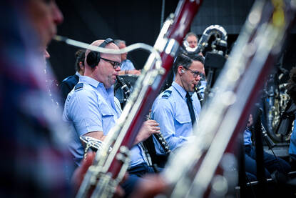 Twee orkestleden met blaasinstrument in de mond.